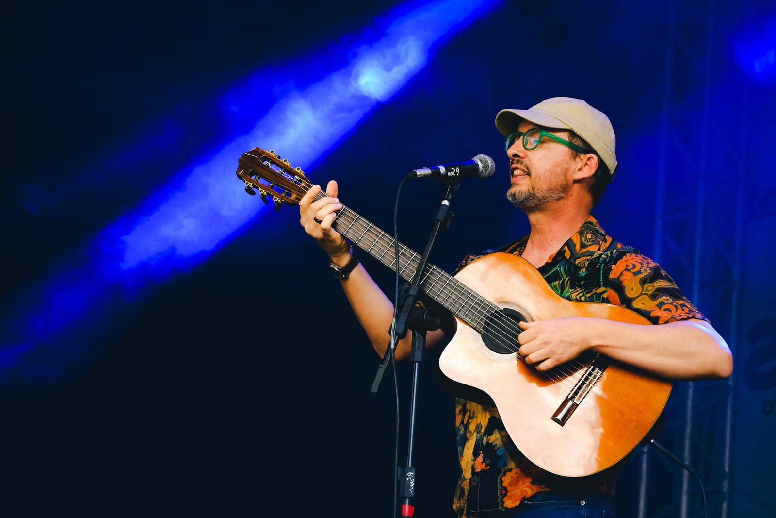 Keiráku — Rafael Longo cantando com o violão no palco, sob luz azul